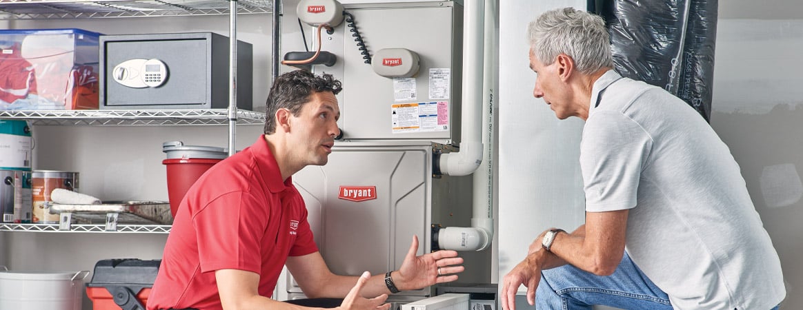 technician showing heating furnace to home owner